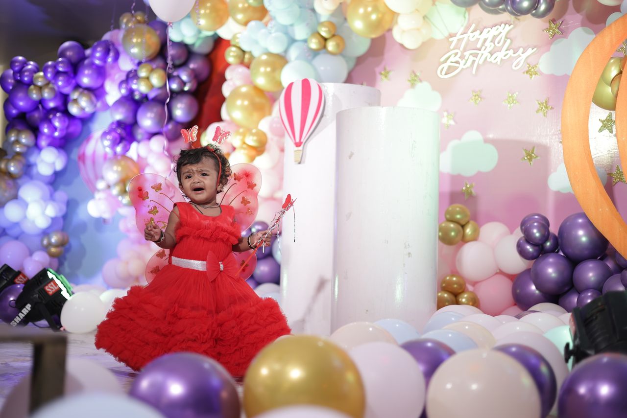 A joyful birthday celebration featuring a little girl dressed as a fairy surrounded by colorful balloons indoors